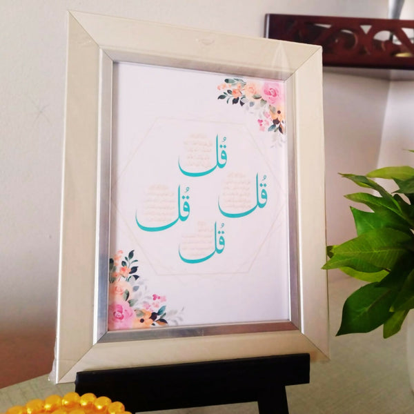 4 Quls Islamic Wall and Desk Art Frame featuring the four Qul verses in elegant Arabic calligraphy, adorned with floral accents in a stylish white frame, displayed on a desk with decorative elements in the background.