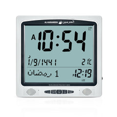 Al-Harameen Azan Clock HA-7009 with digital display, showing prayer times, and featuring adjustable volume control. The clock has a simple setup based on area code and dimensions of 24.5 x 23.5 cm.